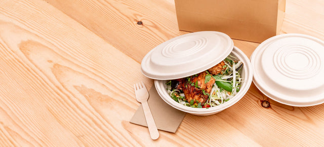 Bagasse dish and lid with napkin and wooden fork.